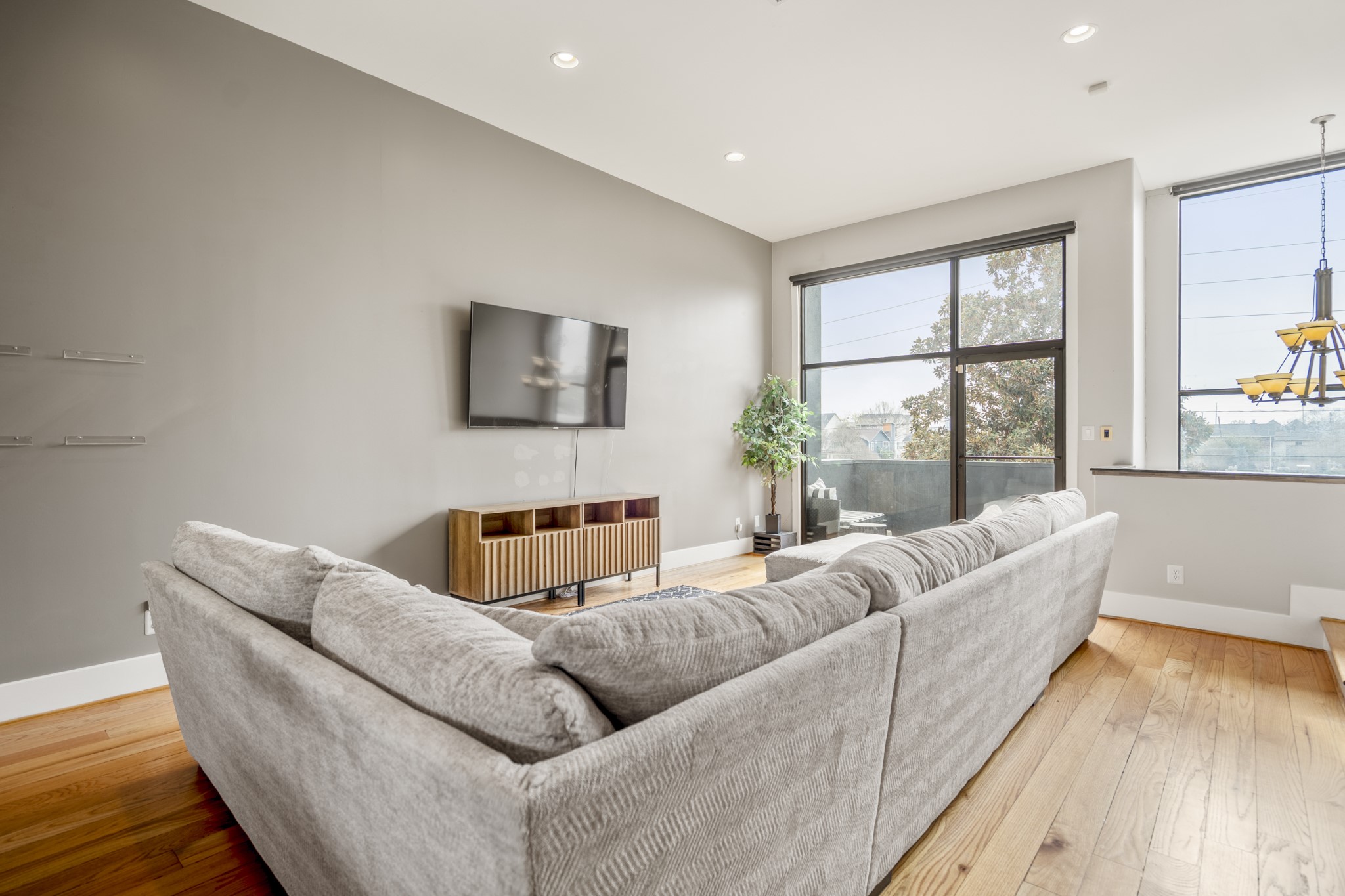 1310 West Dallas Street Houston, TX 77019 - Photo 22 of 50 Viewed from the opposite side, the living room opens toward oversized windows and sliding glass doors that draw in natural light and lead directly to the balcony. The connection to the outdoors adds depth to the space while reinforcing the home’s indoor-outdoor flow and urban setting.