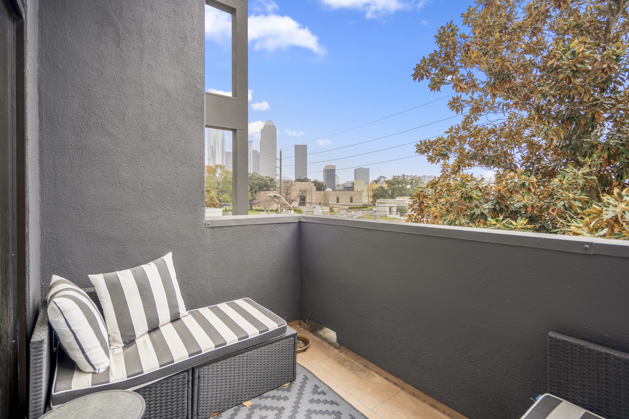 1310 West Dallas Street Houston, TX 77019 - Photo 23 of 50 Stepping outside, the balcony becomes a natural extension of the living room—a tucked-away spot for morning coffee or a quiet reset at the end of the day. From here, you catch glimpses of the skyline framed by mature trees, keeping the view connected to the city while still feeling comfortably private.
