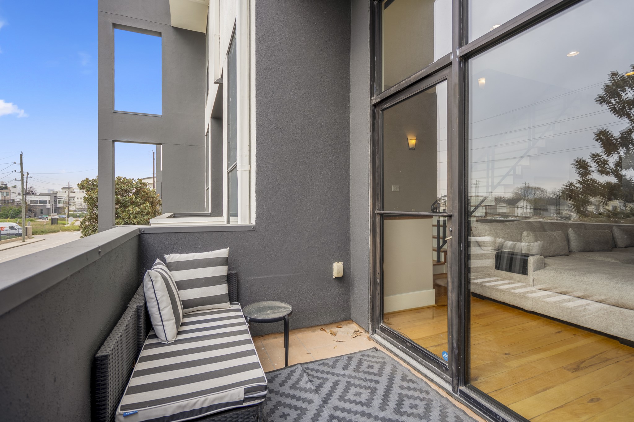 1310 West Dallas Street Houston, TX 77019 - Photo 25 of 50 Looking back toward the living room, the balcony stays closely connected to the main gathering space—glass doors bring the light inside while keeping the outdoor lounge just a step away. It’s easy to picture evenings moving back and forth between the sofa and this quiet perch, with fresh air and city views always within reach.