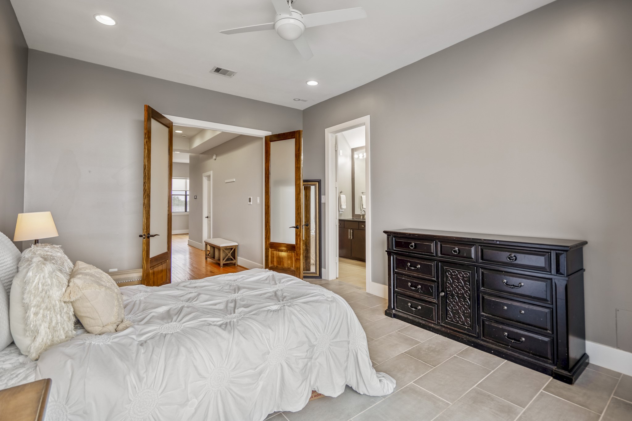 1310 West Dallas Street Houston, TX 77019 - Photo 30 of 50 Light-filled and thoughtfully laid out, the primary suite offers a comfortable retreat with tile flooring, recessed lighting, and a ceiling fan for everyday ease. The bedroom connects directly to the en-suite bath, with the upstairs landing just beyond—creating a private, well-separated space that feels calm and intentional.