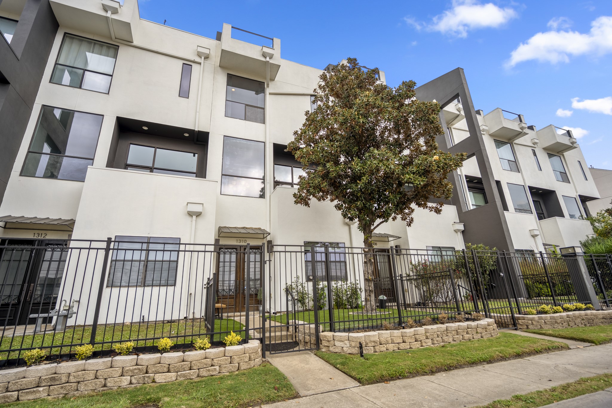 1310 West Dallas Street Houston, TX 77019 - Photo 4 of 50 Street-facing and set behind a secure fence, the home’s contemporary architecture and stacked balconies preview the vertical layout inside, with a private gate opening to a direct entry walk to the front door.