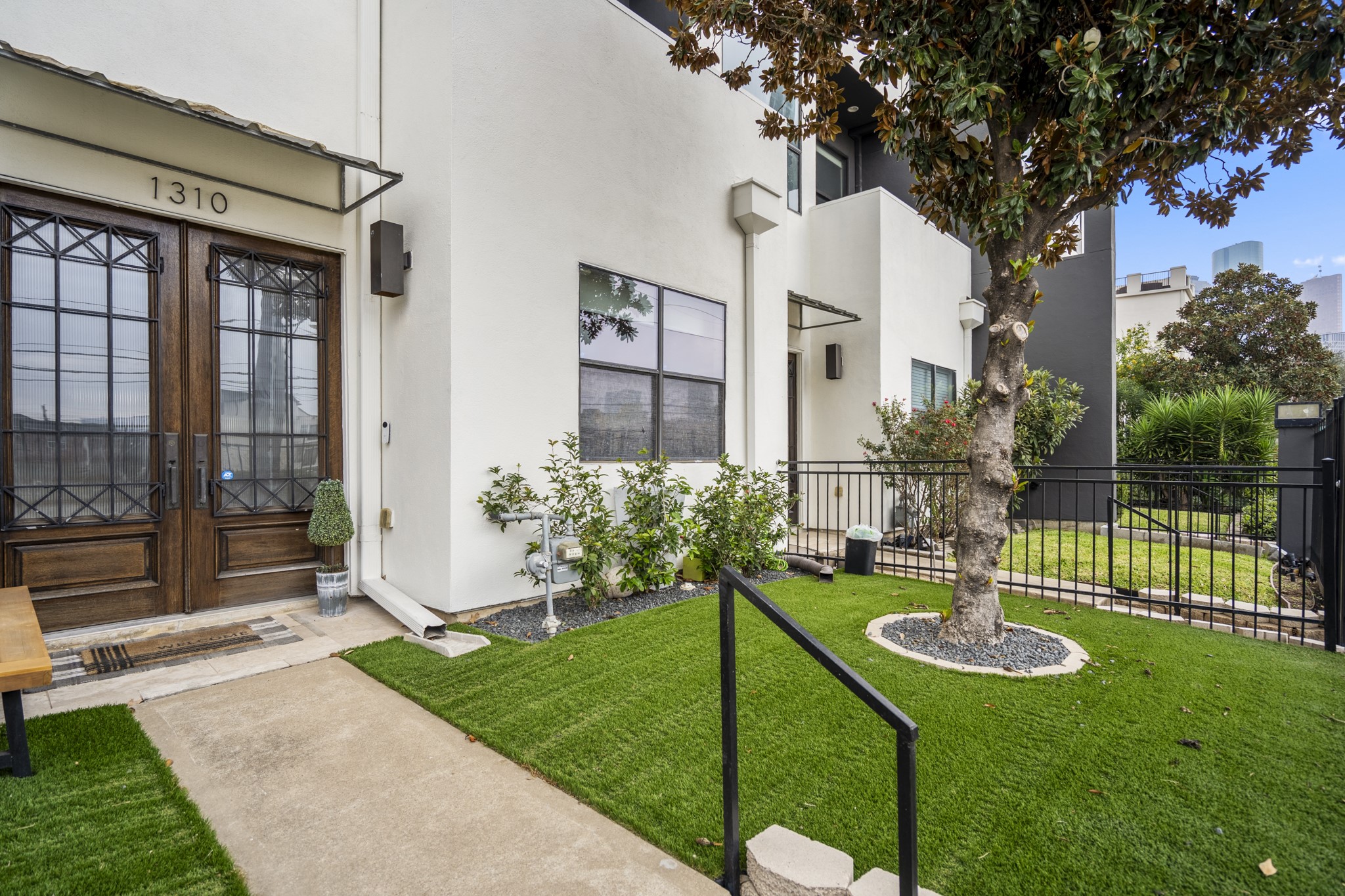 1310 West Dallas Street Houston, TX 77019 - Photo 5 of 50 Inside the gate, the landscaped entry walk feels calm and intentional, with low-maintenance turf adding a fresh, finished look as it guides you toward the front doors—an inviting pause between street and home.