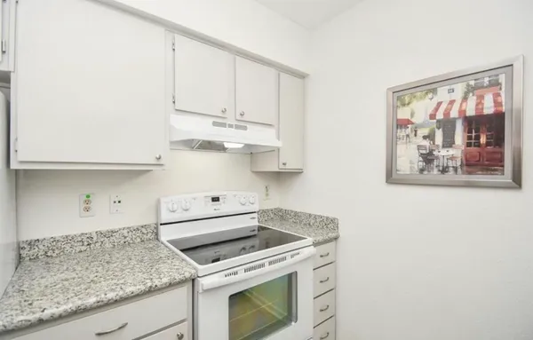 a kitchen with stainless steel appliances granite countertop white cabinets and a stove