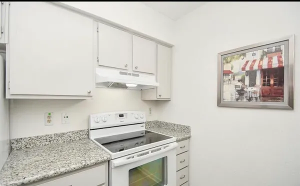 a kitchen with stainless steel appliances granite countertop white cabinets and a stove