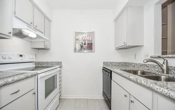 a kitchen with granite countertop a sink stove and cabinets