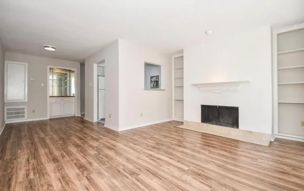 a view of empty room with wooden floor and fireplace