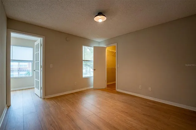 an empty room with wooden floor and windows