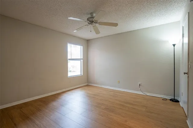 an empty room with wooden floor chandelier fan and windows