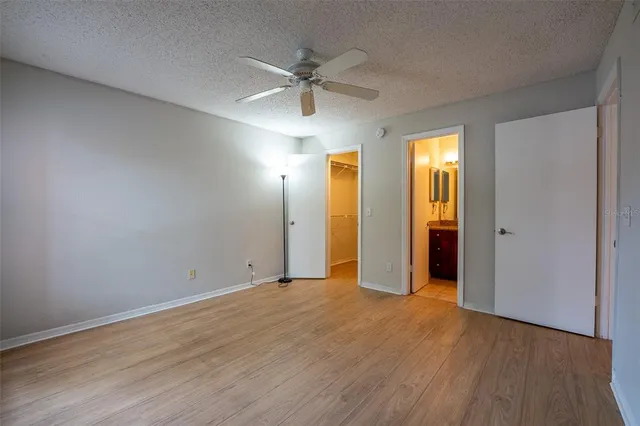 an empty room with wooden floor fan and windows