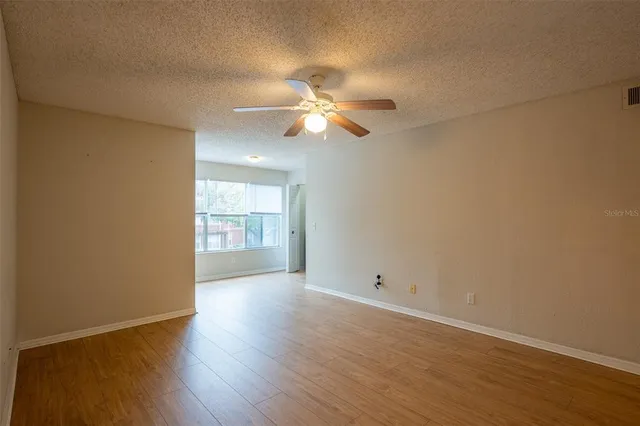 a view of empty room with wooden floor and fan