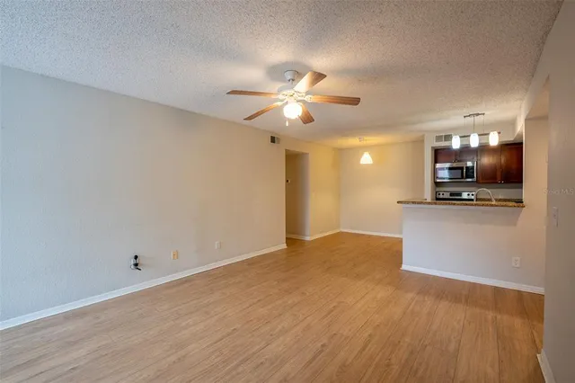 a view of kitchen and empty room with wooden floor