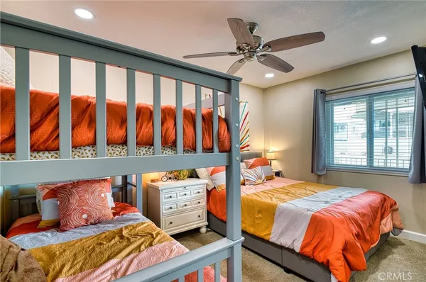 a bedroom with a bed a potted plant on dresser and a window