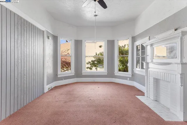 an empty room with chandelier fan and windows