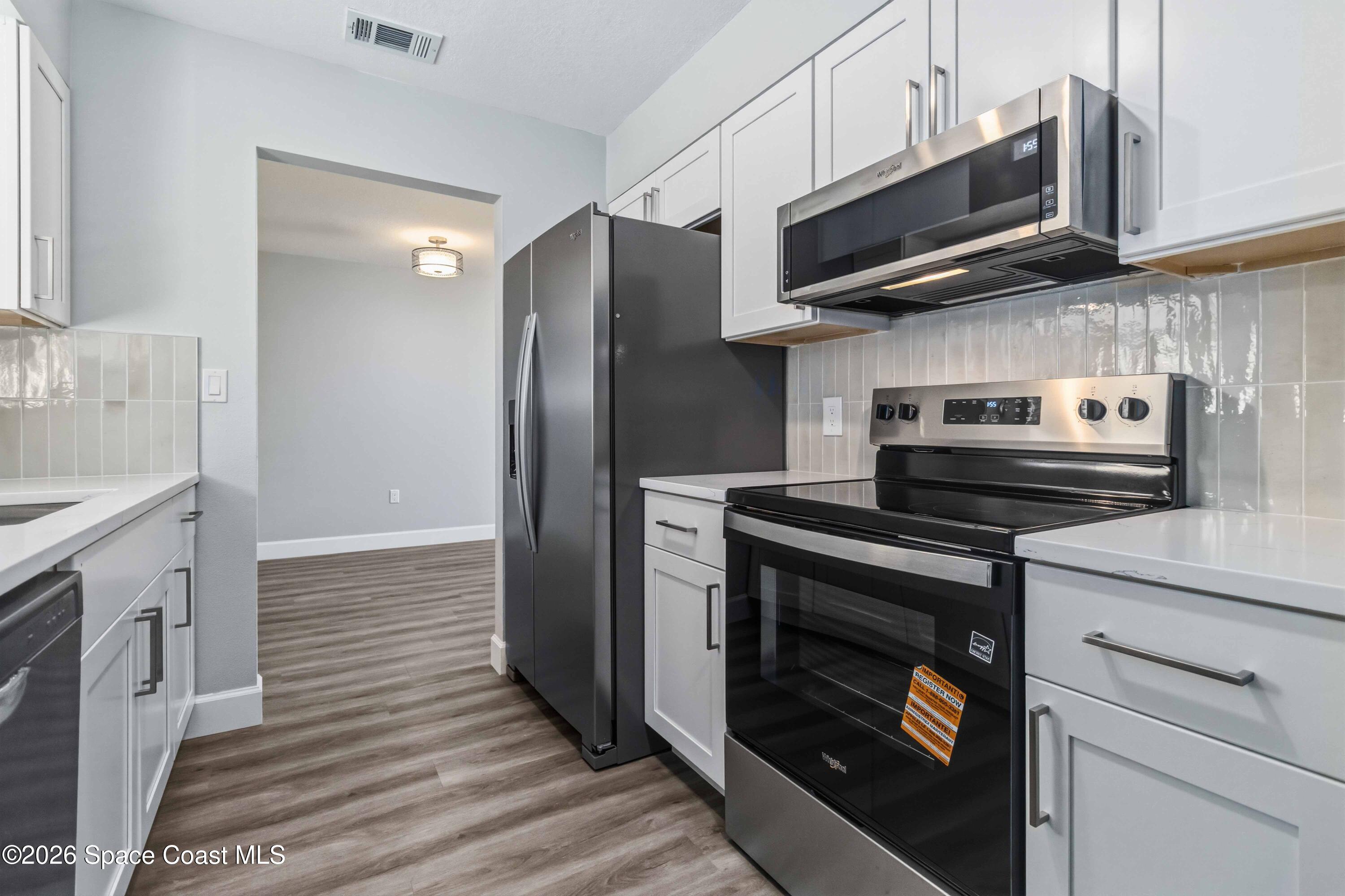 2258 Flower Tree Circle Melbourne, FL 32935 - Photo 11 of 30 a kitchen with stainless steel appliances granite countertop a stove microwave and refrigerator