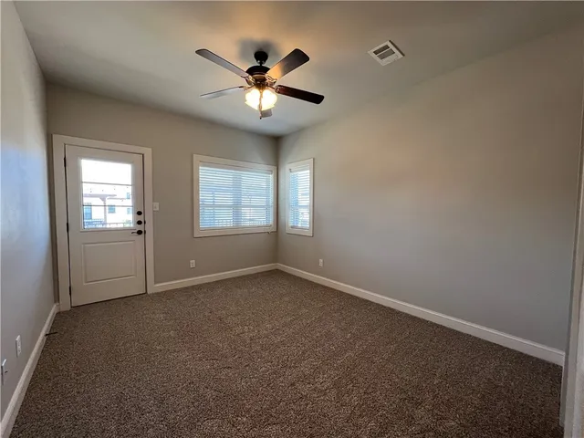 an empty room with windows and fan