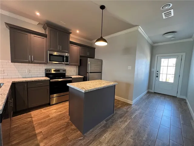 a kitchen with kitchen island a refrigerator stove a sink and dishwasher with wooden floor