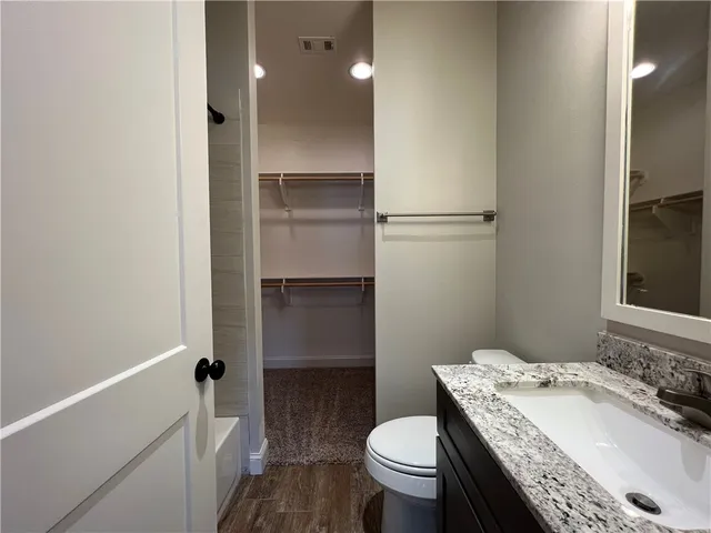 a bathroom with a granite countertop sink toilet and shower