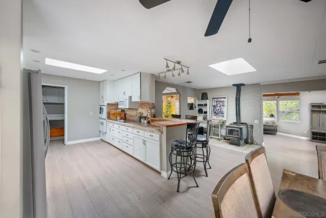 a kitchen with stainless steel appliances granite countertop a stove top oven a sink a dining table and chairs with wooden floor