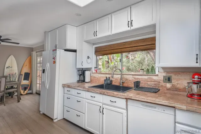 a kitchen with granite countertop a refrigerator a sink a stove a counter space and cabinets