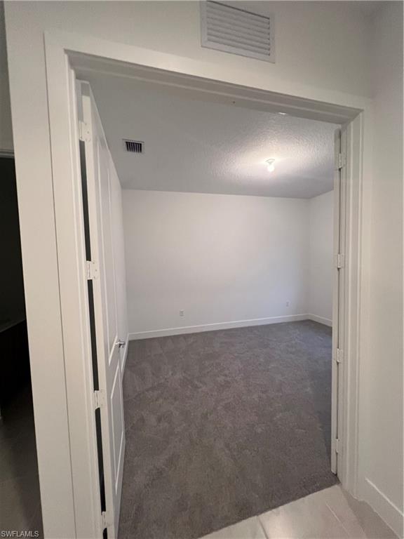 5261 Lamone Ln Avenue Immokalee, FL 34142 - Photo 3 of 14 Empty room with a textured ceiling and dark colored carpet