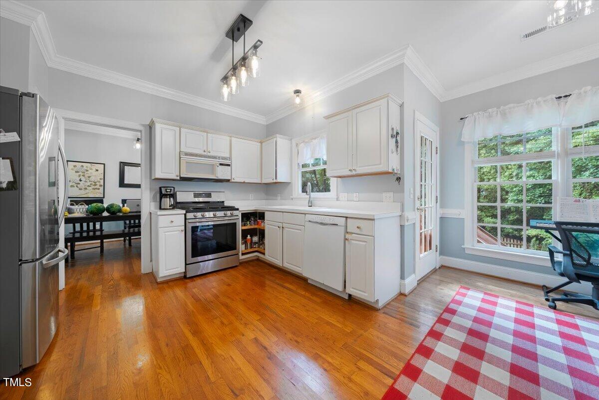 11905 Radner Way Raleigh, NC 27613 - Photo 4 of 35 a kitchen with stainless steel appliances a stove a sink a refrigerator white cabinets and wooden floor