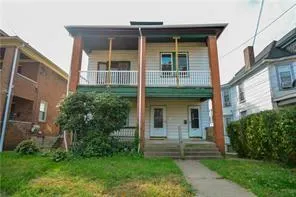 a view of a brick house with a yard potted plants and a table
