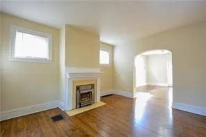 an empty room with wooden floor a fireplace and windows