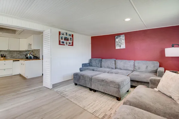 a living room with couches and kitchen view with wooden floor
