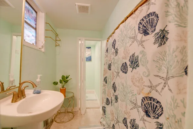 a bathroom with a sink and mirror with bathtub