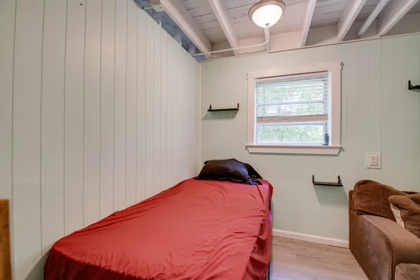 a bedroom with a bed and chair with the wooden floor
