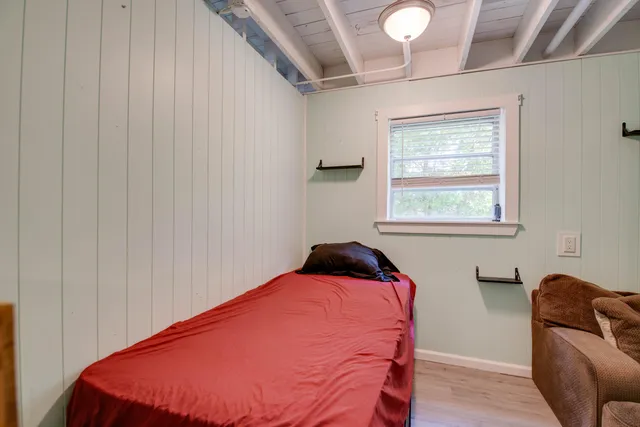 a bedroom with a bed and chair with the wooden floor
