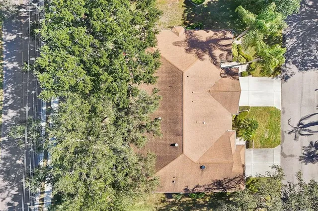 an aerial view of a residential houses with outdoor space and trees