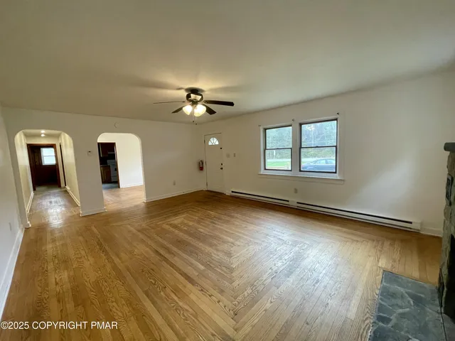 a view of an empty room with window and wooden floor