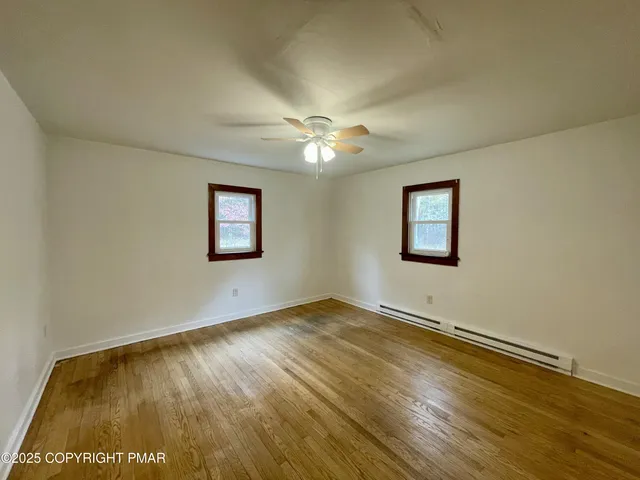 a view of an empty room with window and chandelier fan