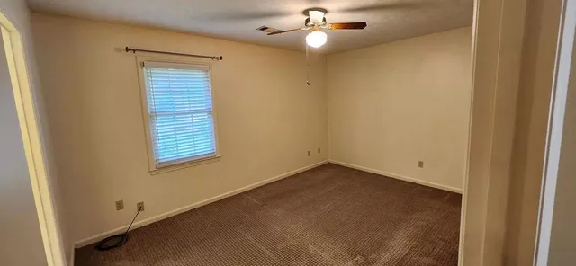 an empty room with a window and ceiling fan