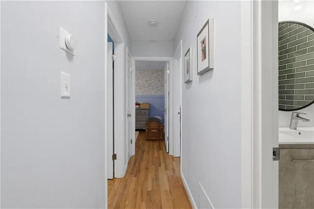 a view of a hallway with wooden floor and a bathroom