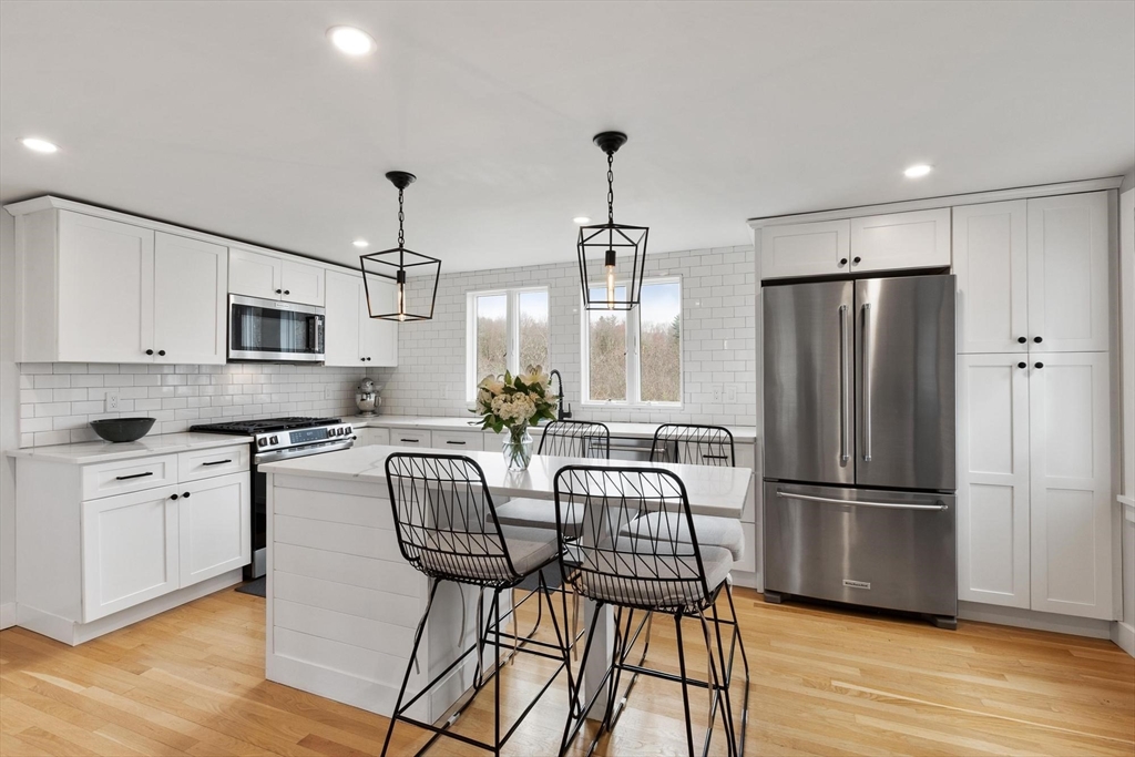 68 Still River Road Harvard, MA 01451 - Photo 7 of 41 a kitchen with stainless steel appliances granite countertop a refrigerator a stove a sink dishwasher a dining table and chairs with wooden floor