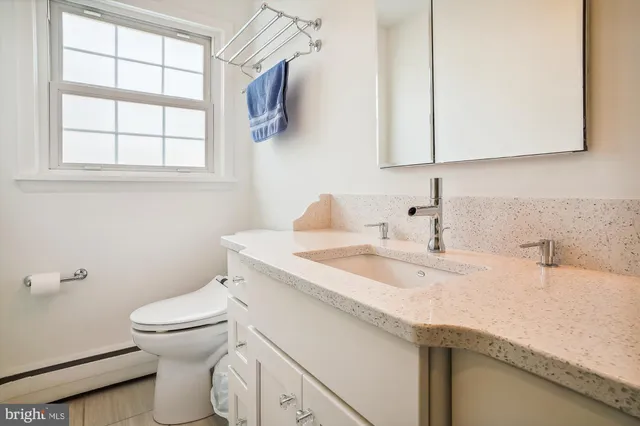 a bathroom with a granite countertop sink a toilet and a mirror