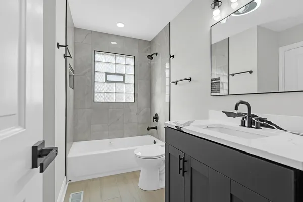 a bathroom with a granite countertop sink a toilet and bathtub