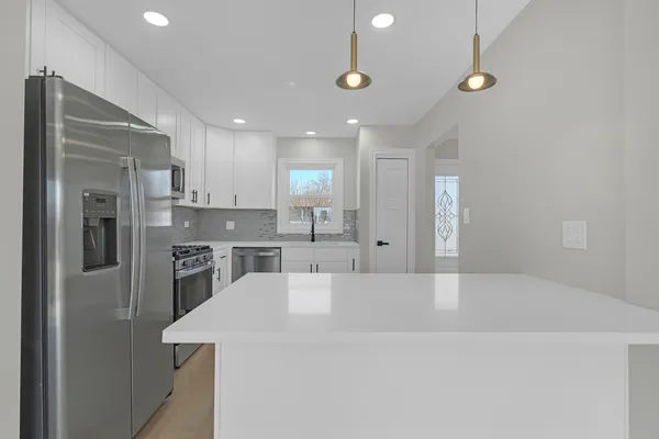 a large white kitchen with a refrigerator a sink and a stove
