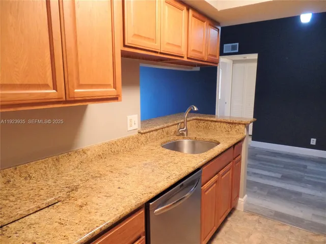 a kitchen with stainless steel appliances granite countertop a sink and a wooden cabinets