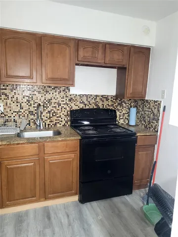 a view of kitchen and empty room with wooden floor