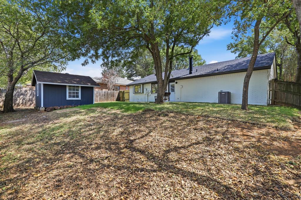 3405 Mill Ridge Street Bedford, TX 76021 - Photo 26 of 32 Expansive backyard featuring a detached storage shed, mature trees, and a private wooden fence