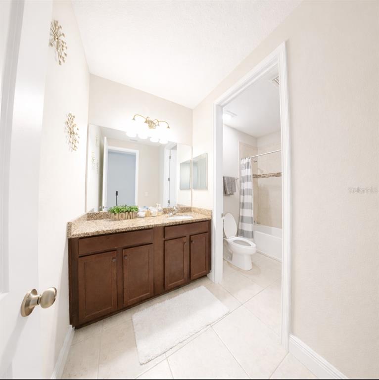 1216 Old Windsor Way Spring Hill, FL 34609 - Photo 23 of 31 a spacious bathroom with a granite countertop sink a toilet and a mirror