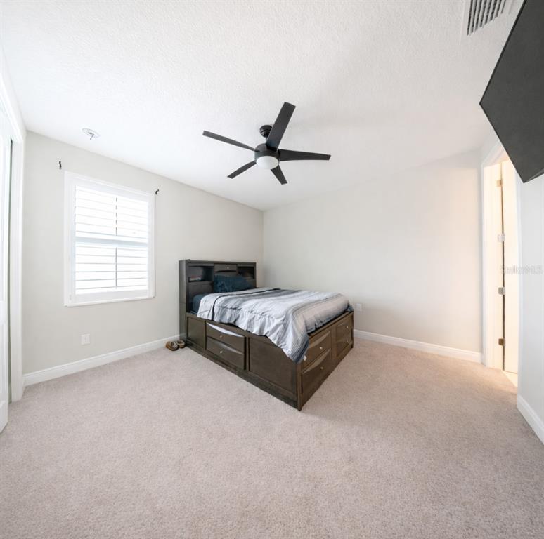 1216 Old Windsor Way Spring Hill, FL 34609 - Photo 24 of 31 a bedroom with a bed and a ceiling fan