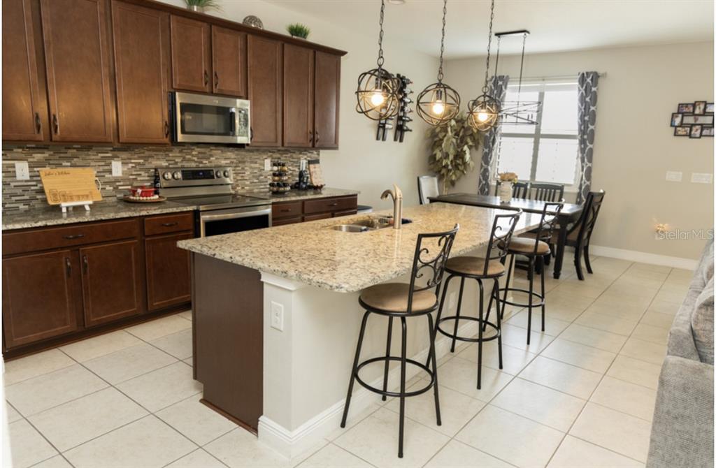 1216 Old Windsor Way Spring Hill, FL 34609 - Photo 9 of 31 a kitchen with stainless steel appliances granite countertop a stove a sink and a microwave