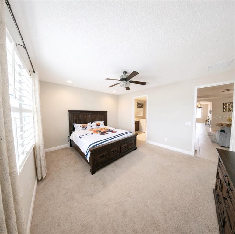 1216 Old Windsor Way Spring Hill, FL 34609 - Photo 10 of 31 a spacious bedroom with a bed and a chandelier
