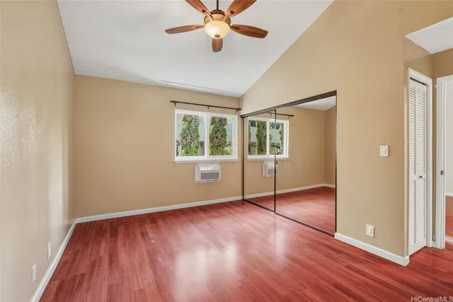 an empty room with wooden floor fan and windows