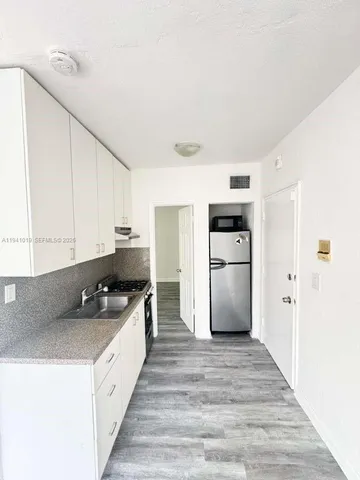 a kitchen with granite countertop a refrigerator and a stove top oven