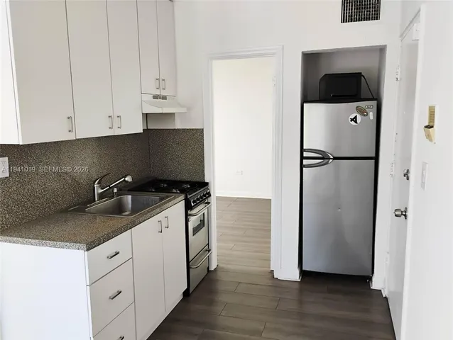a kitchen with a refrigerator sink and cabinets